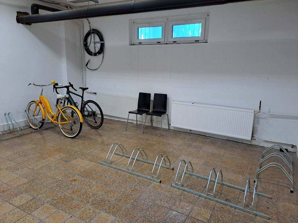 Bicykliareň so stojanmi na bicykle, pri stene stoja dva bicykle