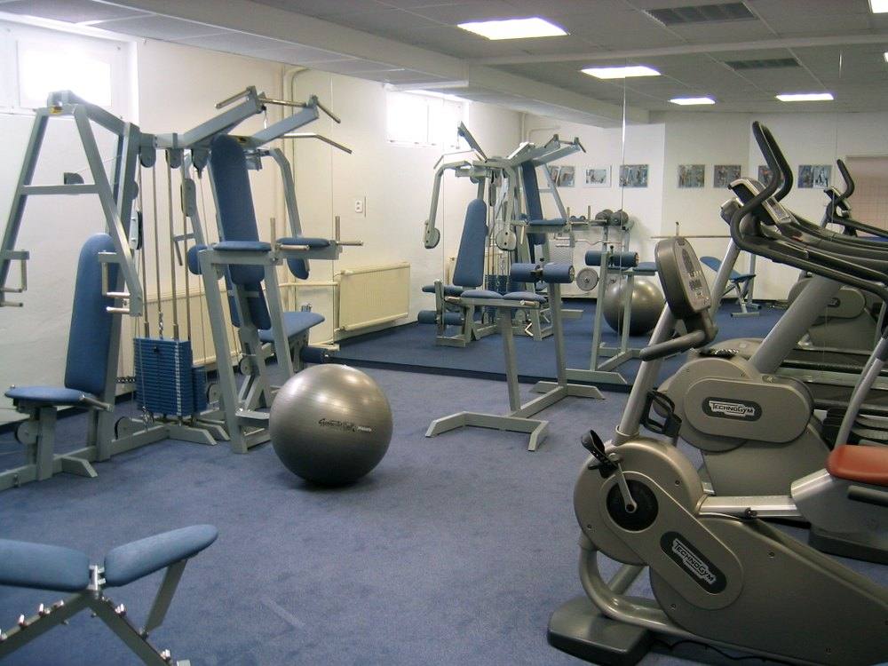 Fitness miestnosť s posilňovacími strojmi, kardio strojom, veľkou loptou a zrkadlovou stenou