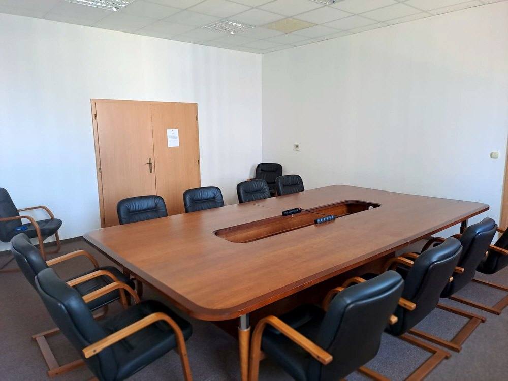 Zasadacia miestnosť s veľkým dreveným stolom a tmavými koženými kreslami dookola